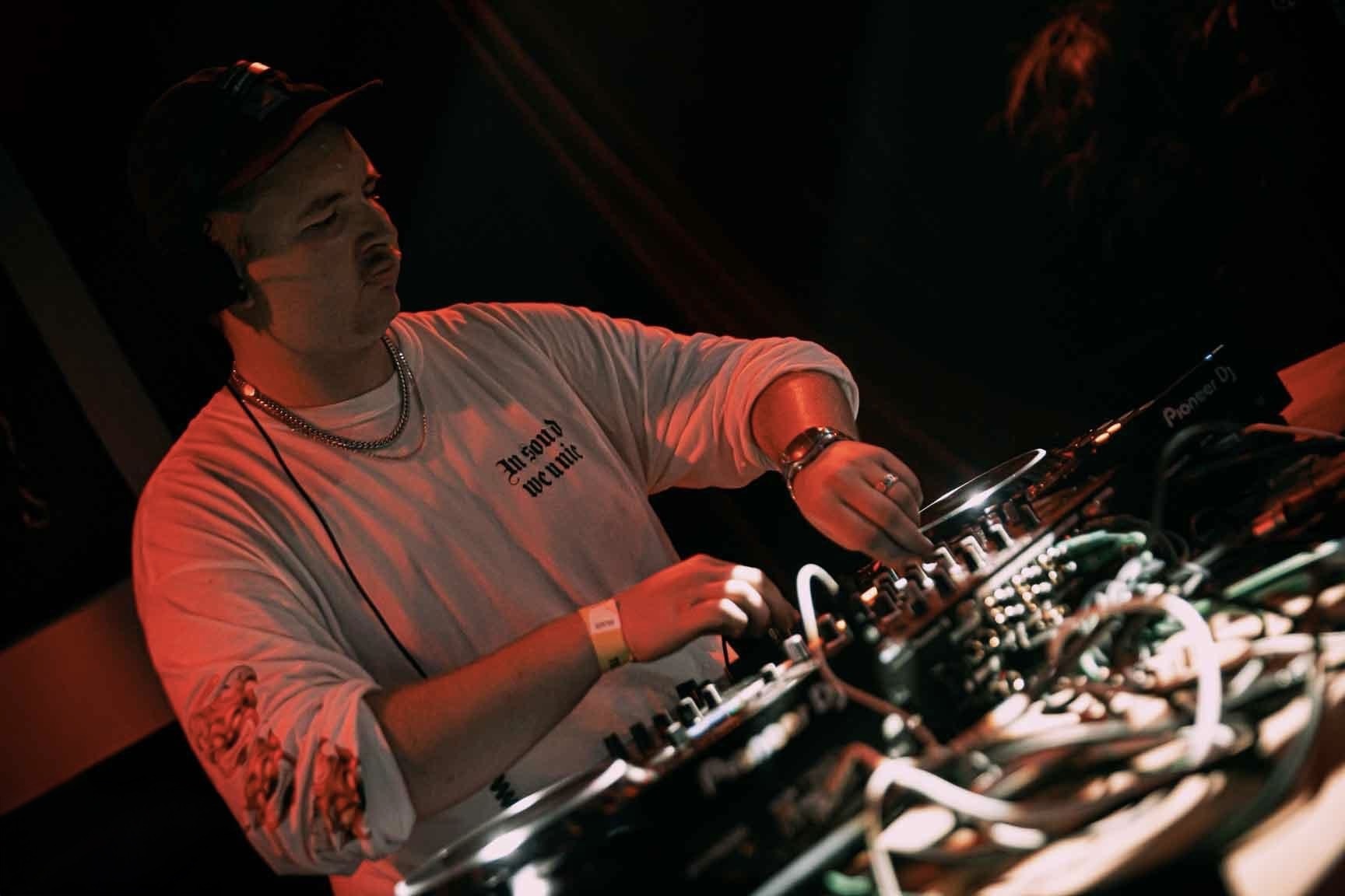 REEZA performing behind the decks in red stage light
